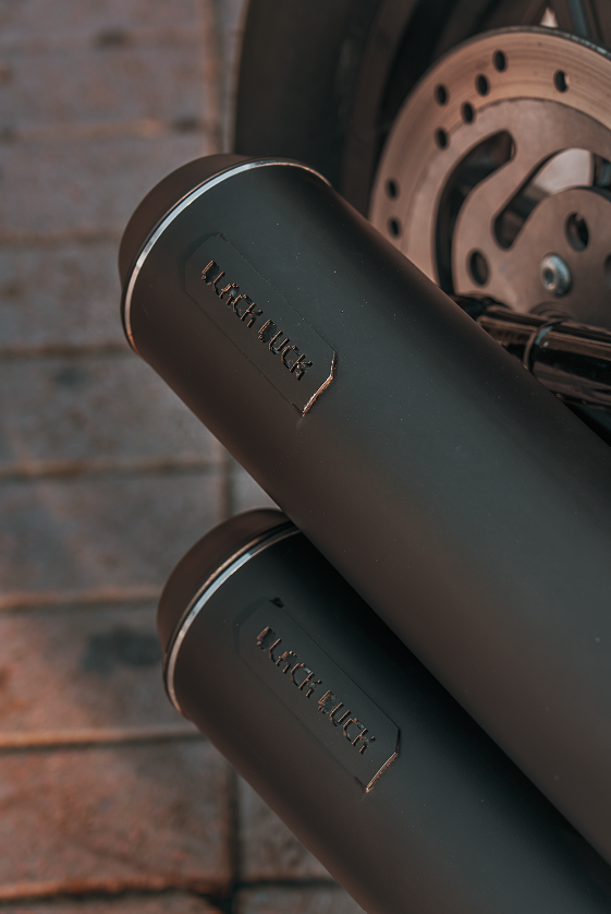 Close-up of Black Duck Tech Bombardier 2+2 exhausts for Harley-Davidson Softail with logo detail in black finish