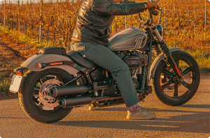 Harley Davidson Softail with Black Duck Bombardier exhaust, rider in a field at sunset, CE approved and lifetime warranty